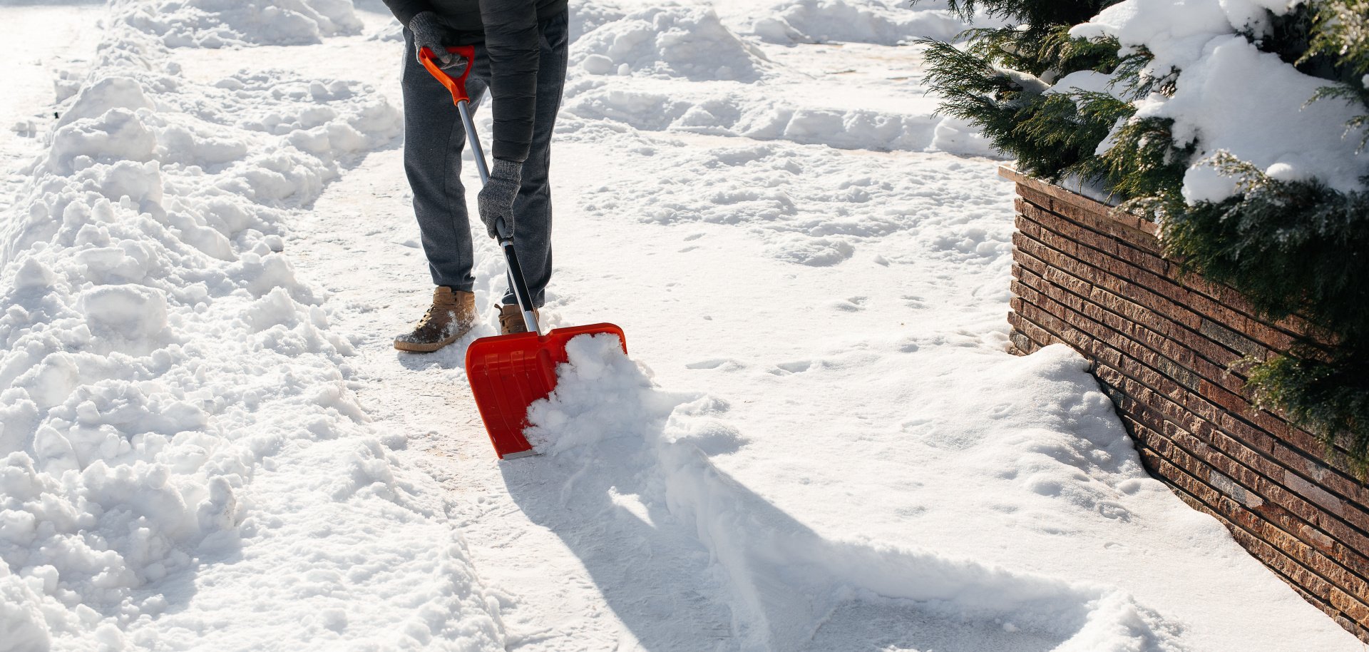 Close-up of a man cleaning and clearing snow in front of the house on a sunny and frosty day. Cleaning the street from snow on a winter day. Snowfall, and a severe snowstorm in winter