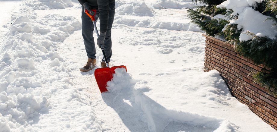 Close-up of a man cleaning and clearing snow in front of the house on a sunny and frosty day. Cleaning the street from snow on a winter day. Snowfall, and a severe snowstorm in winter Close-up of a man cleaning and clearing snow in front of the house on a sunny and frosty day. Cleaning the street from snow on a winter day. Snowfall, and a severe snowstorm in winter