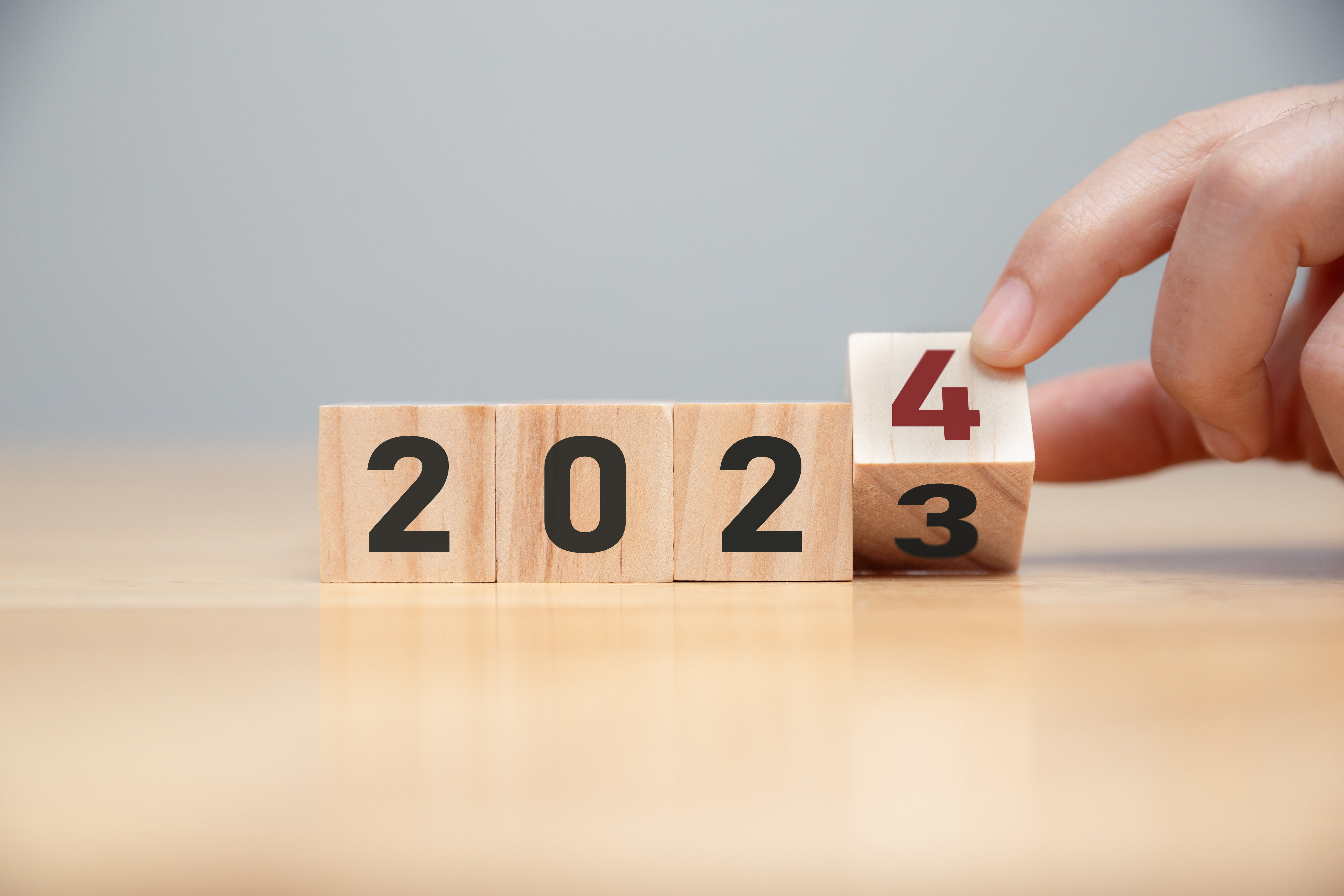 Hand of man flip wooden cube from 2023 to 2024.