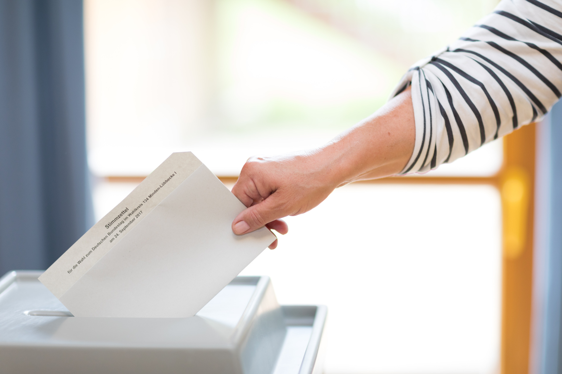 Stimmzettel wird in Wahlurne geworfen