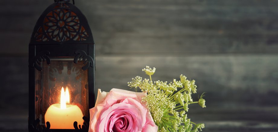 Memorial candle and flowers on wooden background