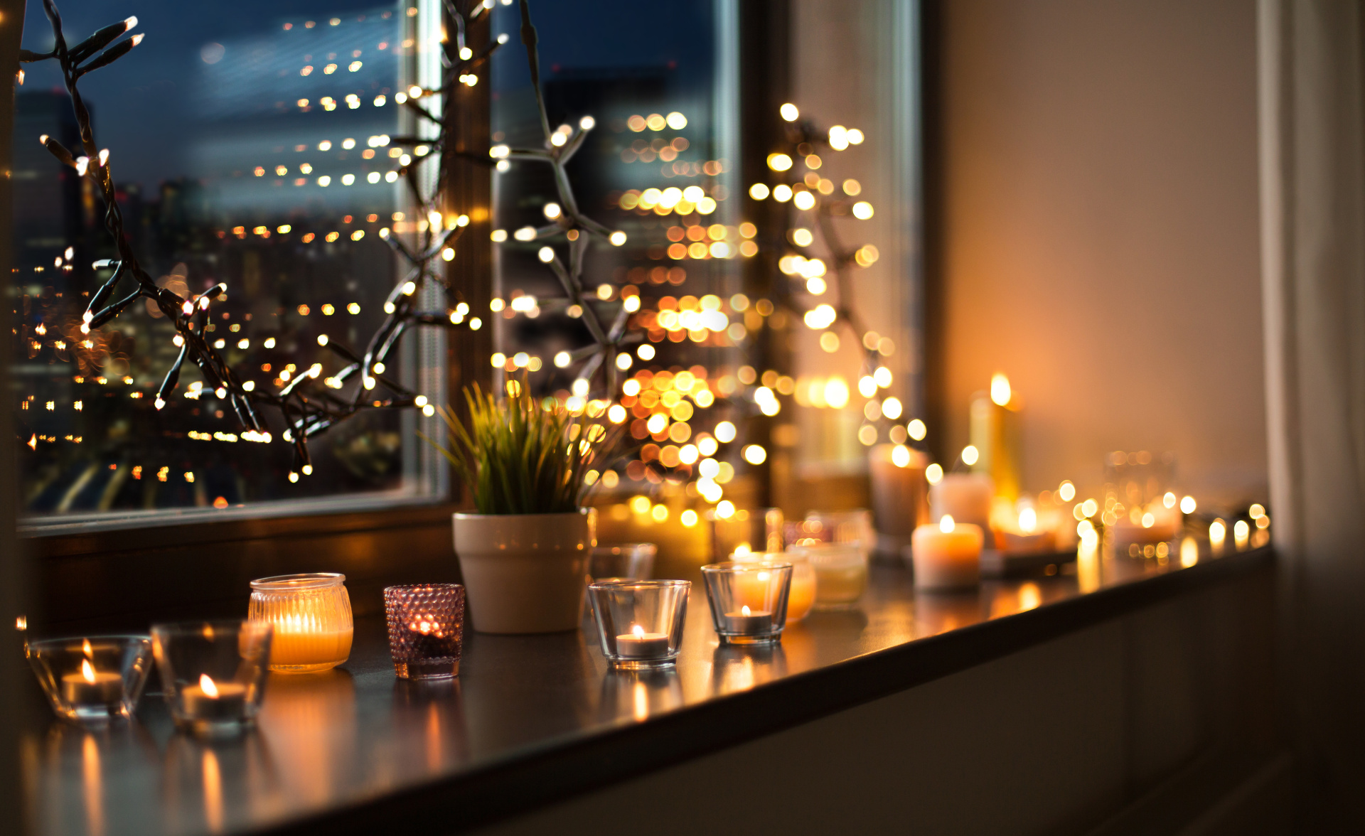 candles burning on window sill with garland lights candles burning on window sill with garland lights