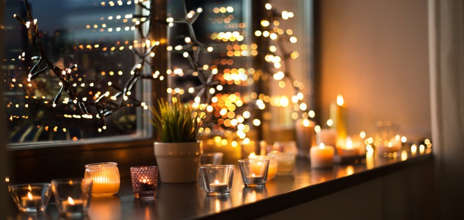 candles burning on window sill with garland lights