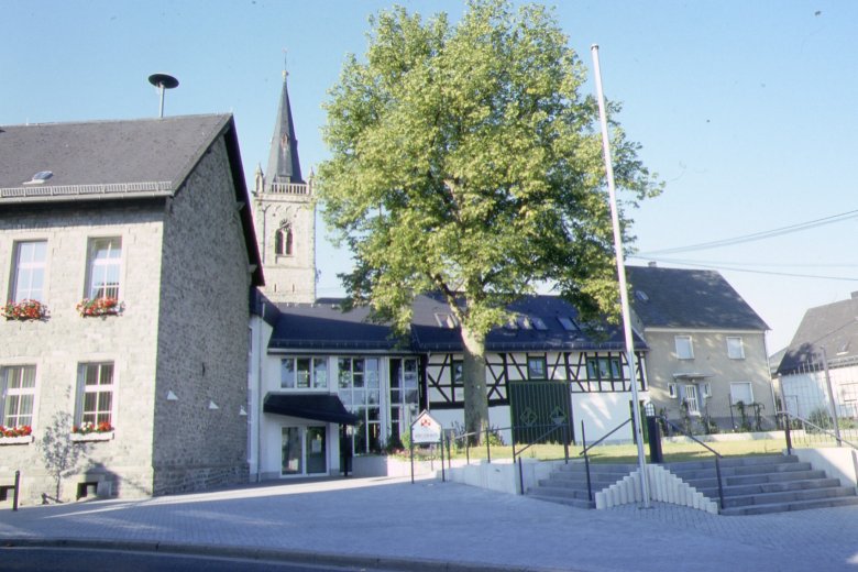 Bürgerhaus Vorderseite mit Kirchturm im Hintergrund